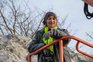 Jelena Rundqvist står uppe i en lift nära bergväggen iklädd arbetskläder.