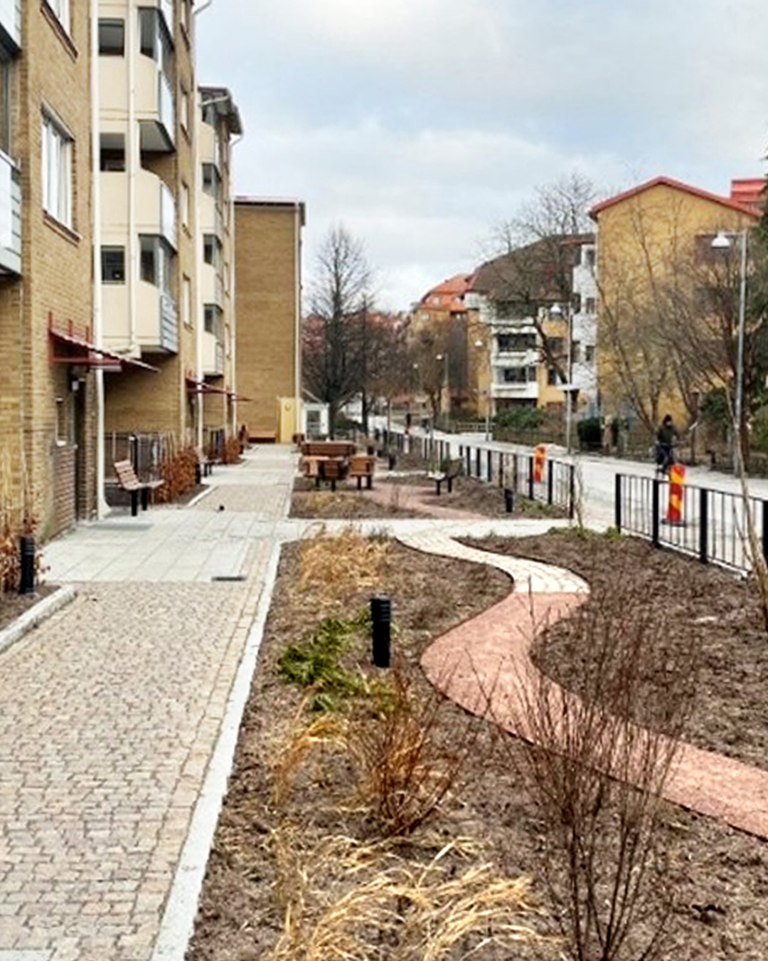 En husfasad till vänster och framför den en liten trädgård