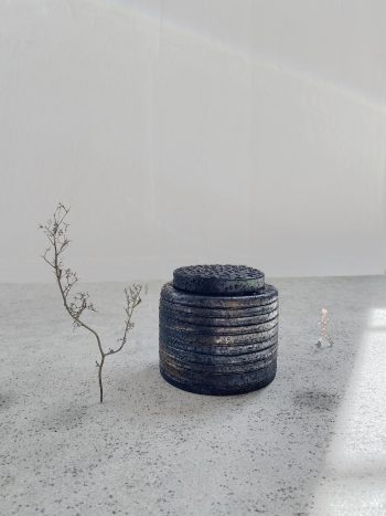 Skiss av Nina Canells "Pitch Drop Pavilion (700 years)". Regnet framhäver basaltens oljeskimrande yta. Modell av den runda paviljongen när det regnar. Regndropparna gör att den mörka ytan får en oljeskimrande glans.